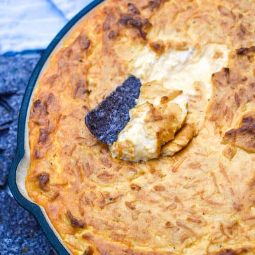 a blue tortilla chip stuck in a skillet of smoked buffalo chicken dip