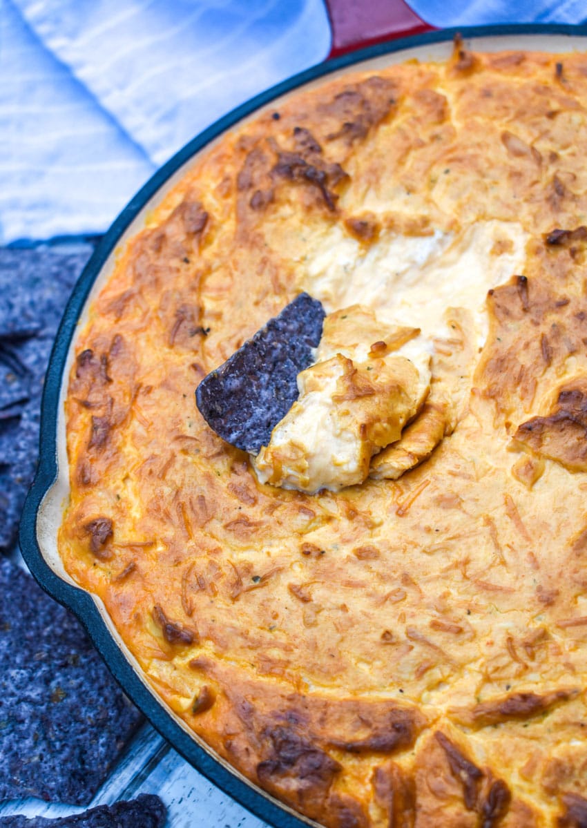 a blue tortilla chip stuck in a skillet of smoked buffalo chicken dip