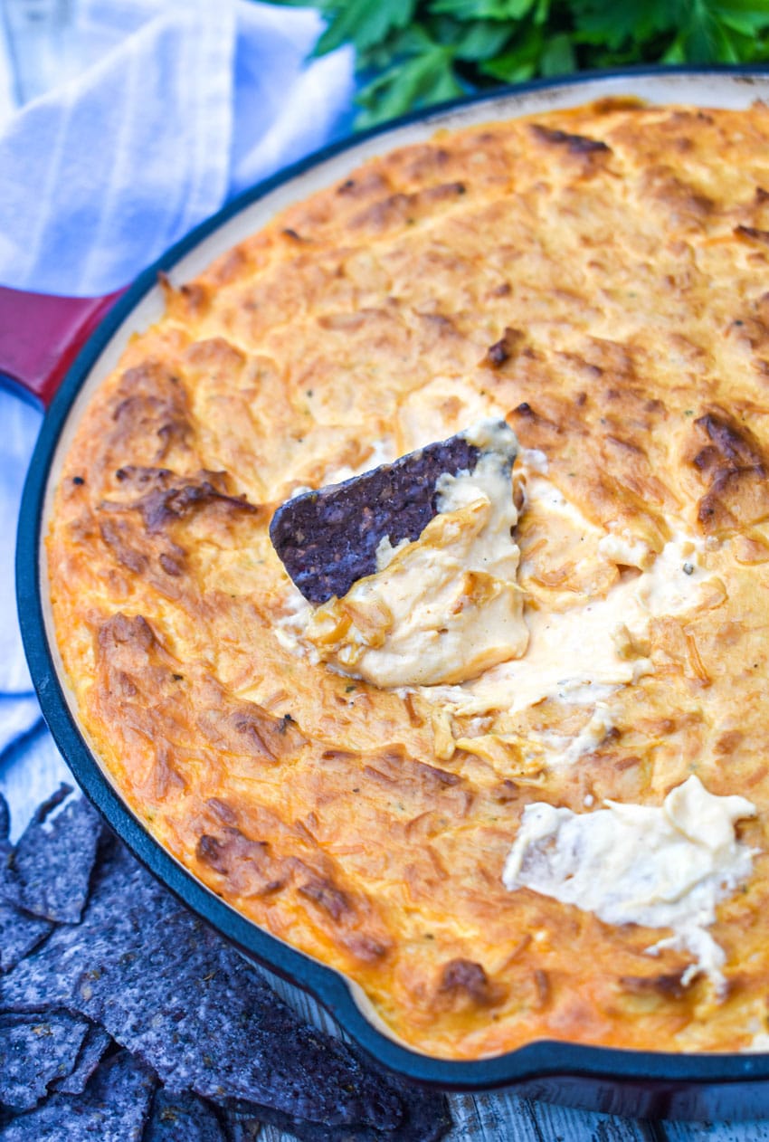 a blue tortilla chip stuck in a skillet of smoked buffalo chicken dip
