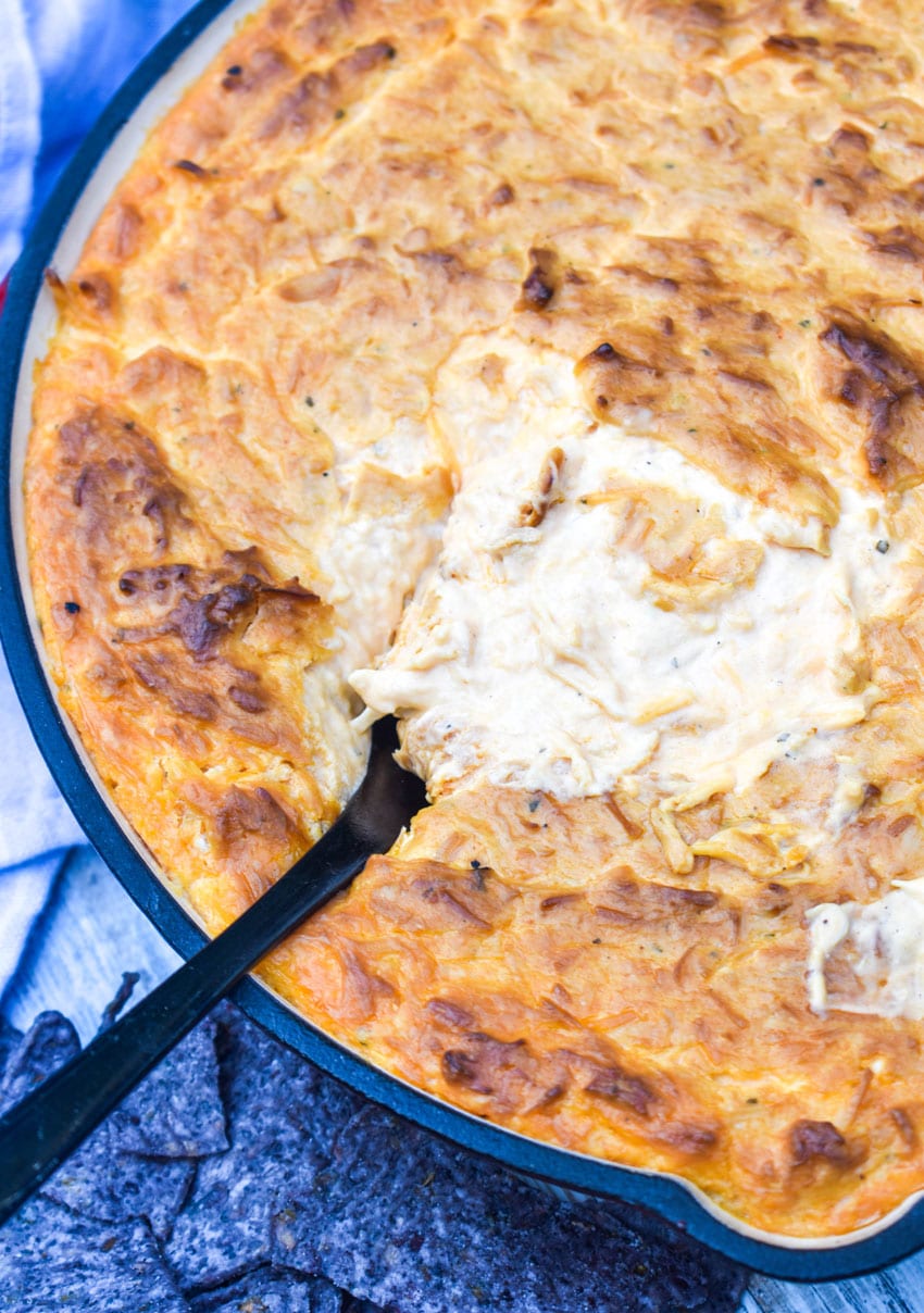 a black spoon stuck in a skillet of smoked buffalo chicken dip