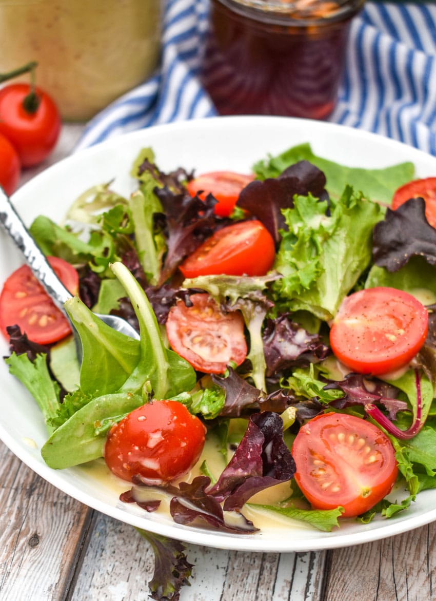 easy honey mustard dressing coated tossed salad in a shallow white bowl