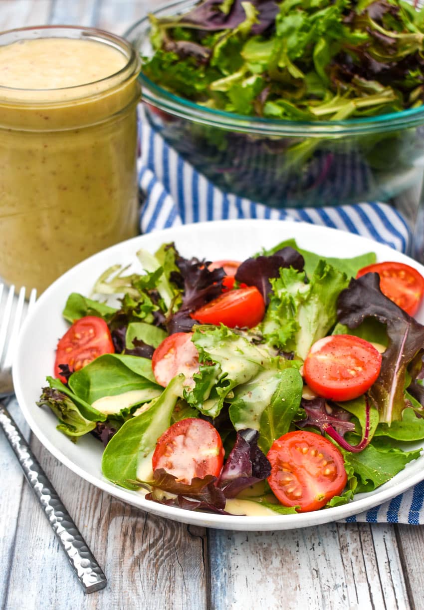 honey mustard dressing on a simple salad in a shallow white bowl