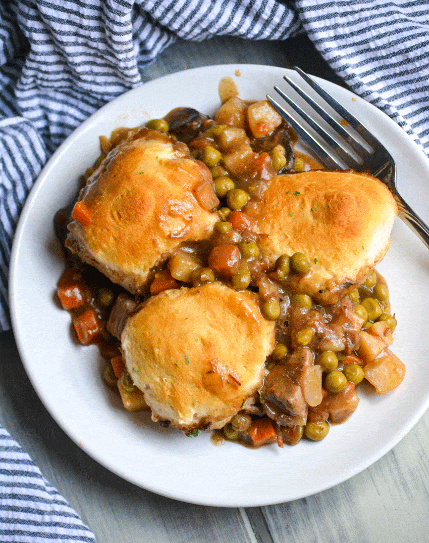 beef pot pie with biscuits on a white plate with a silver fork resting on the side