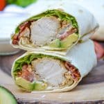 california club chicken wraps stacked on a wooden cutting board