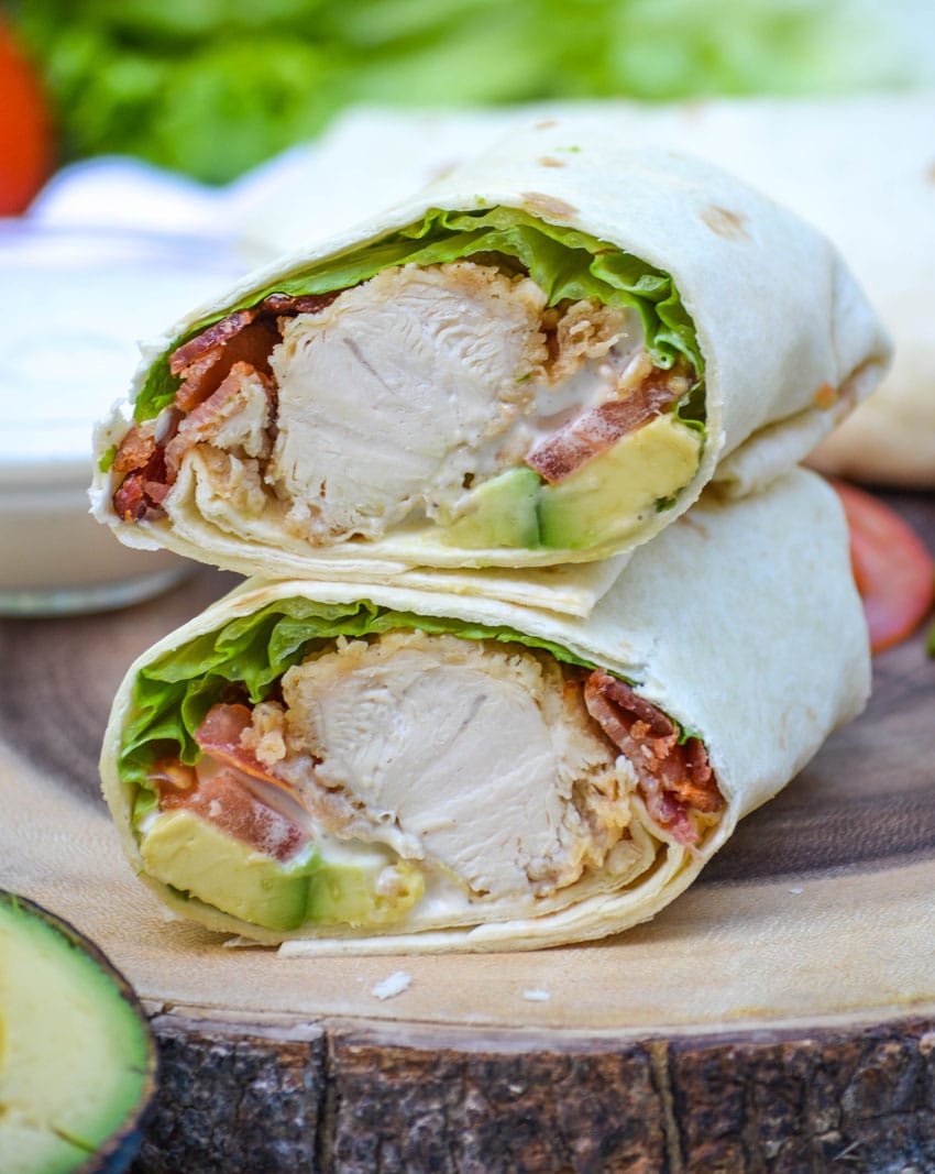 california club chicken wraps stacked on a wooden cutting board