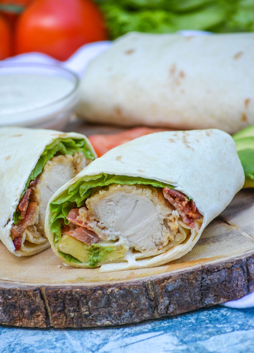california club chicken wraps stacked on a wooden cutting board