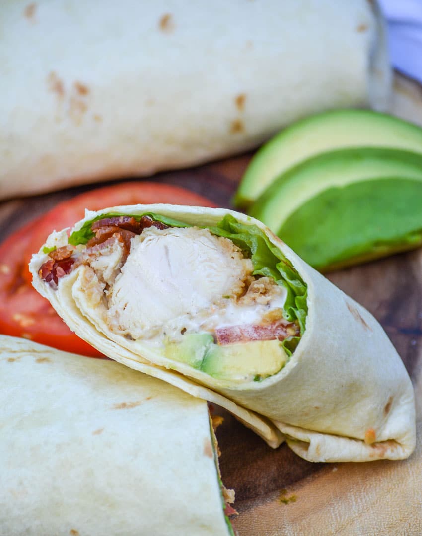 california club chicken wraps stacked on a wooden cutting board