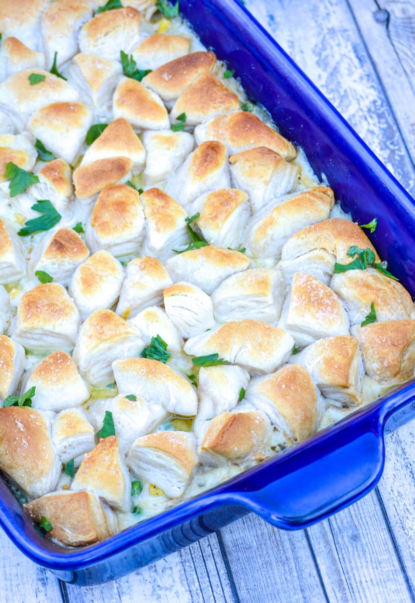 chicken pot pie casserole topped with biscuits in a blue baking dish