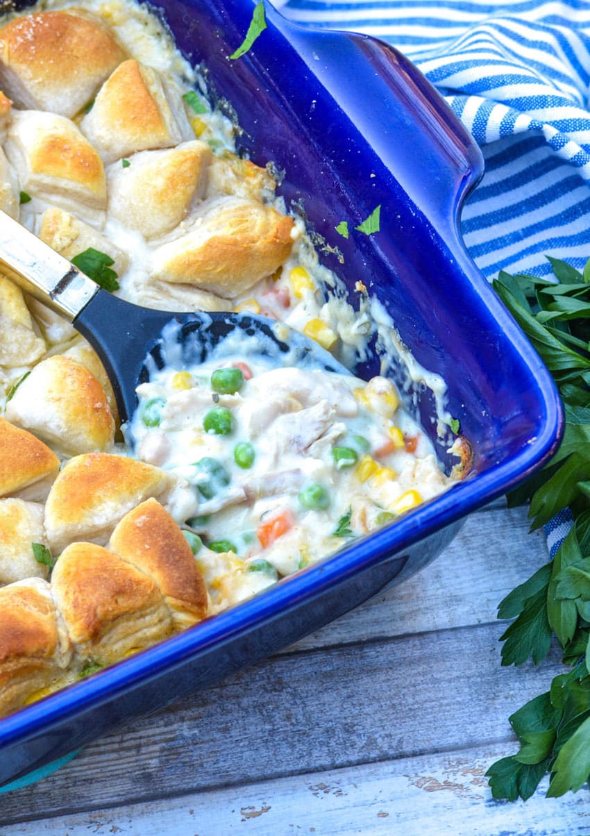 a spoon scooping chicken pot pie filling out of a casserole dish