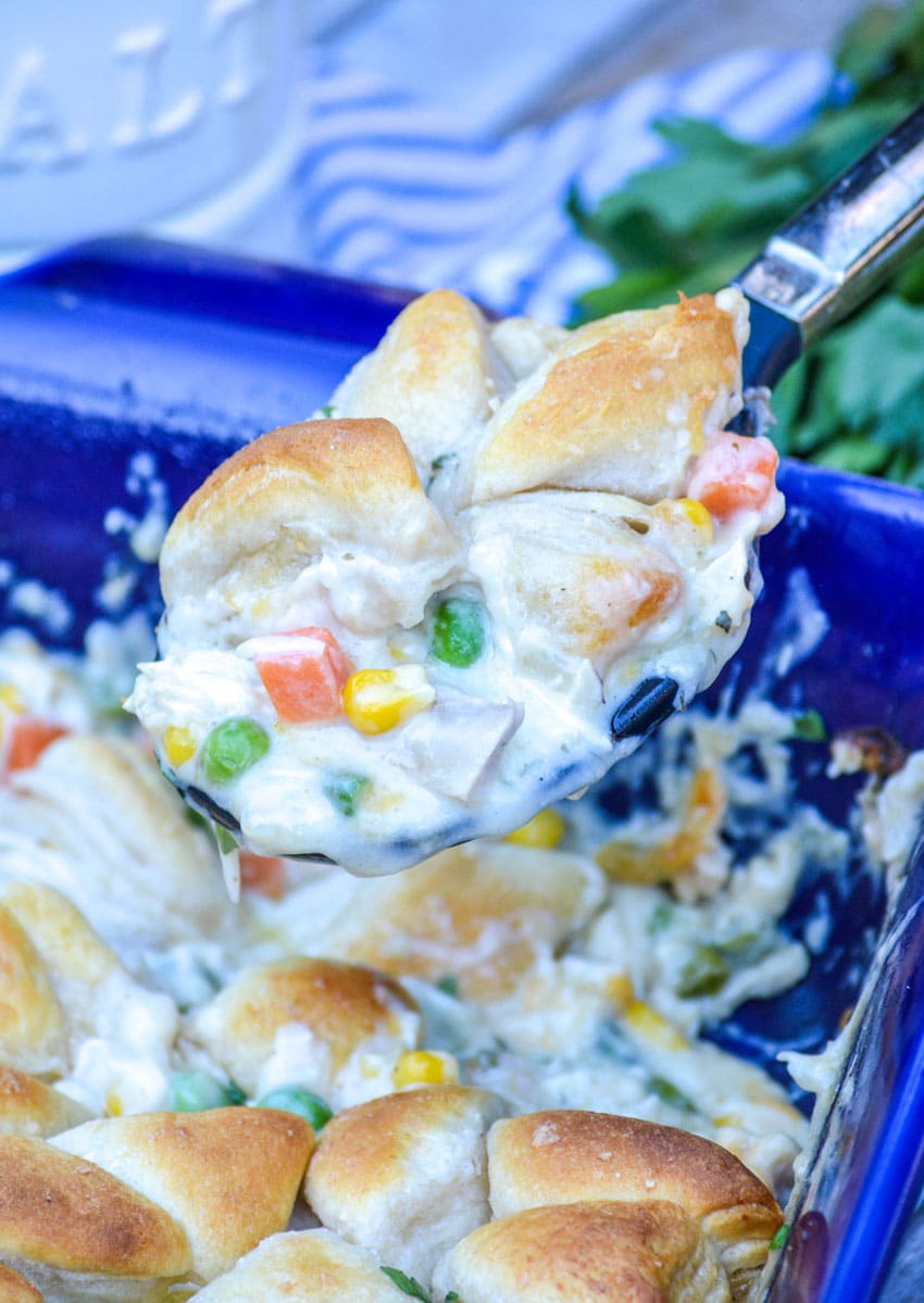 a spoon scooping chicken pot pie filling out of a casserole dish
