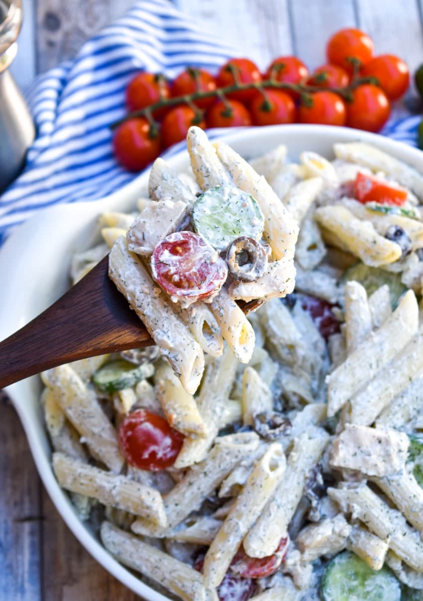 a wooden spoon holding up a scoop of easy Greek pasta salad
