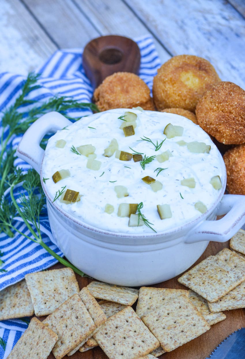 creamy dill pickle dip in a gray bowl surrounded by crackers