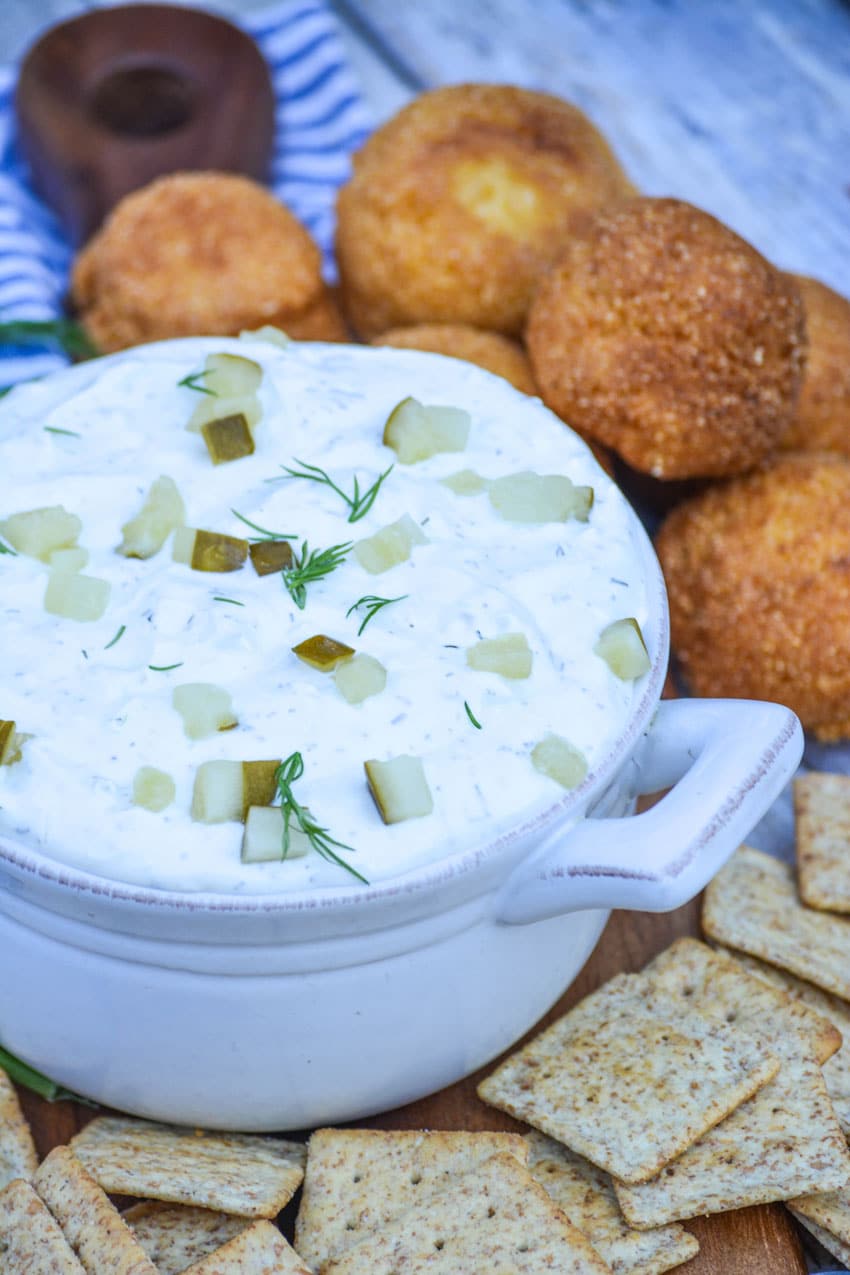 creamy dill pickle dip in a gray bowl surrounded by crackers