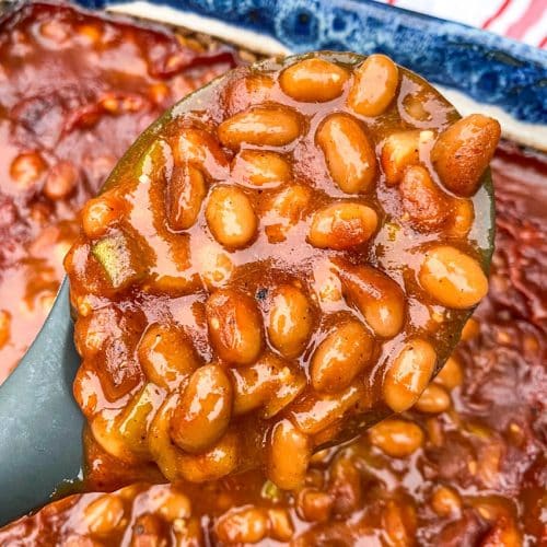 a serving spoon holding up a scoop of smoked baked beans
