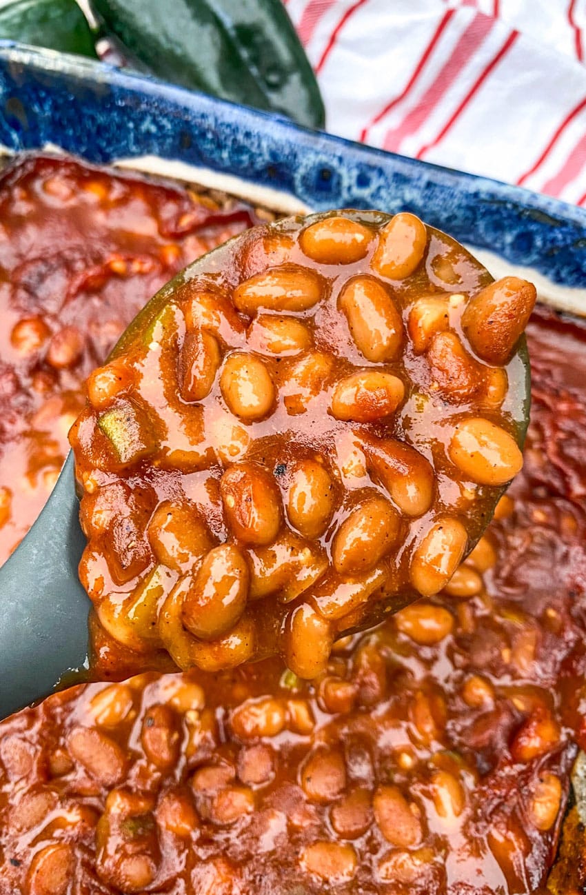 a serving spoon holding up a scoop of smoked baked beans