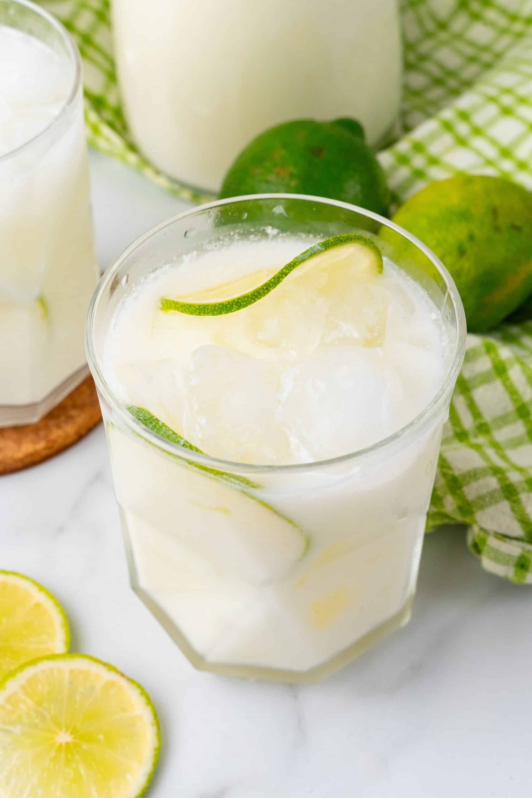 Brazilian Lemonade (Viral TikTok Recipe) creamy Brazilian lemonade in a drinking glass with slices of lime and ice cubes