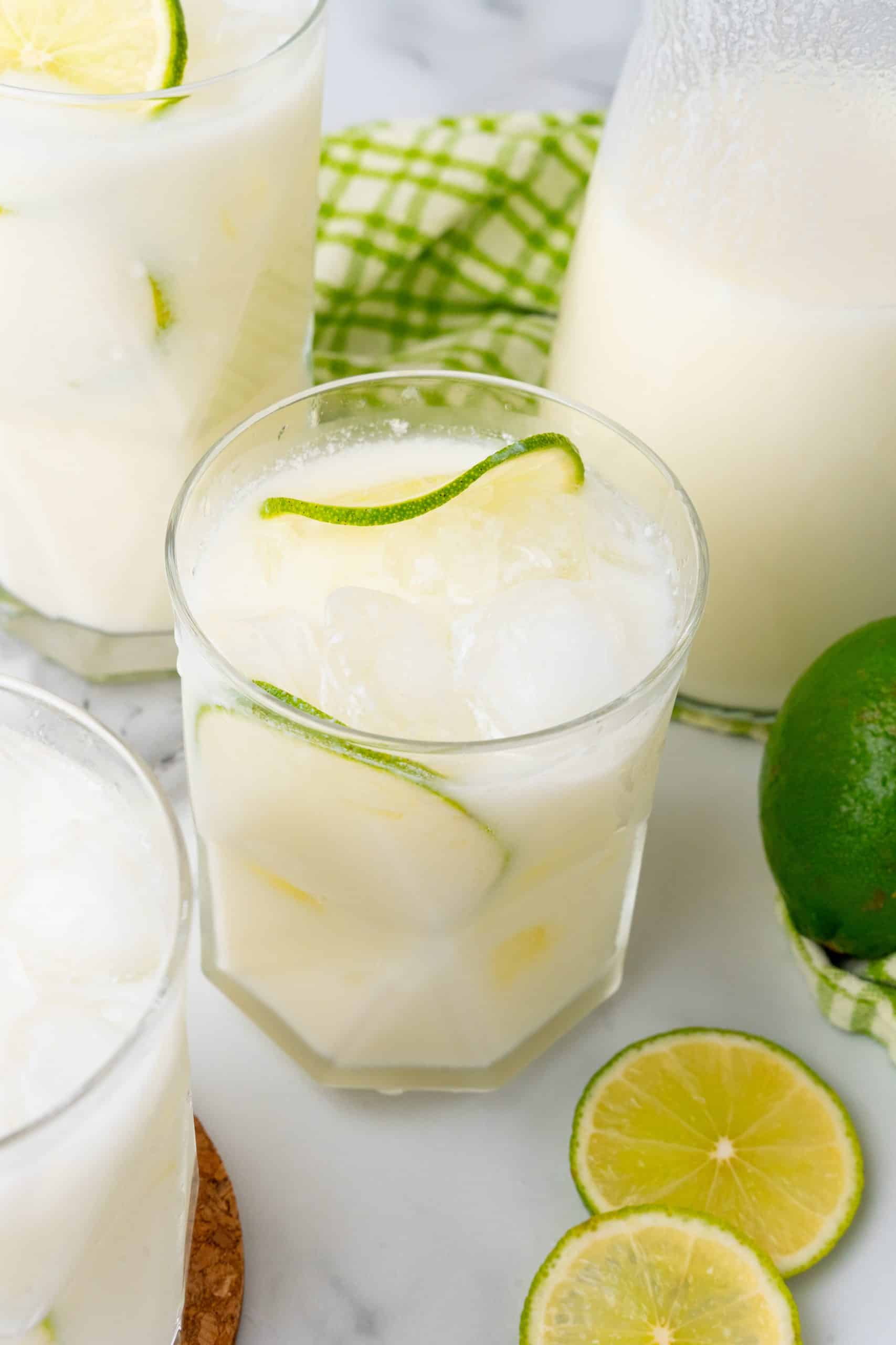 creamy Brazilian lemonade in a drinking glass with slices of lime and ice cubes