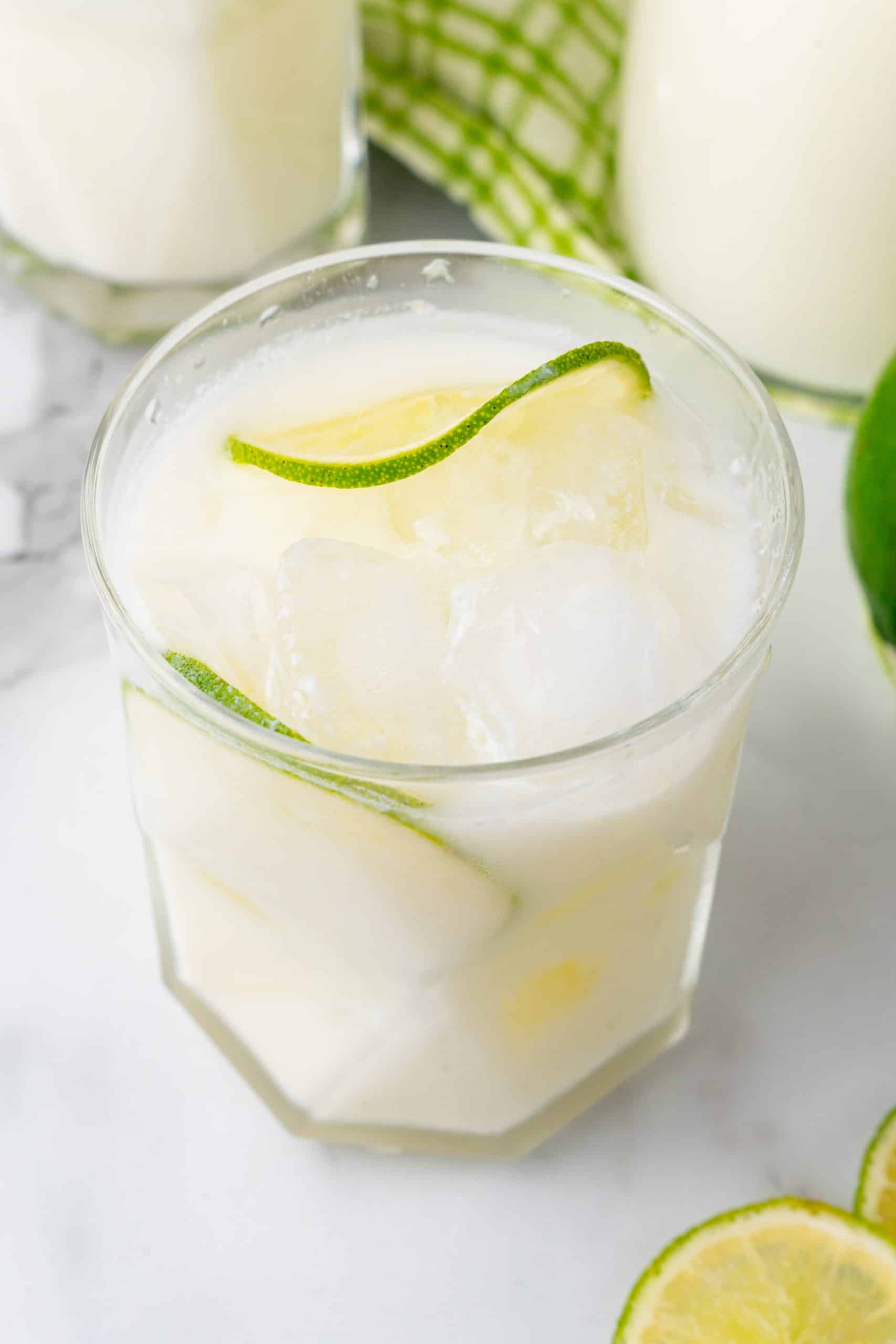 creamy Brazilian lemonade in a drinking glass with slices of lime and ice cubes