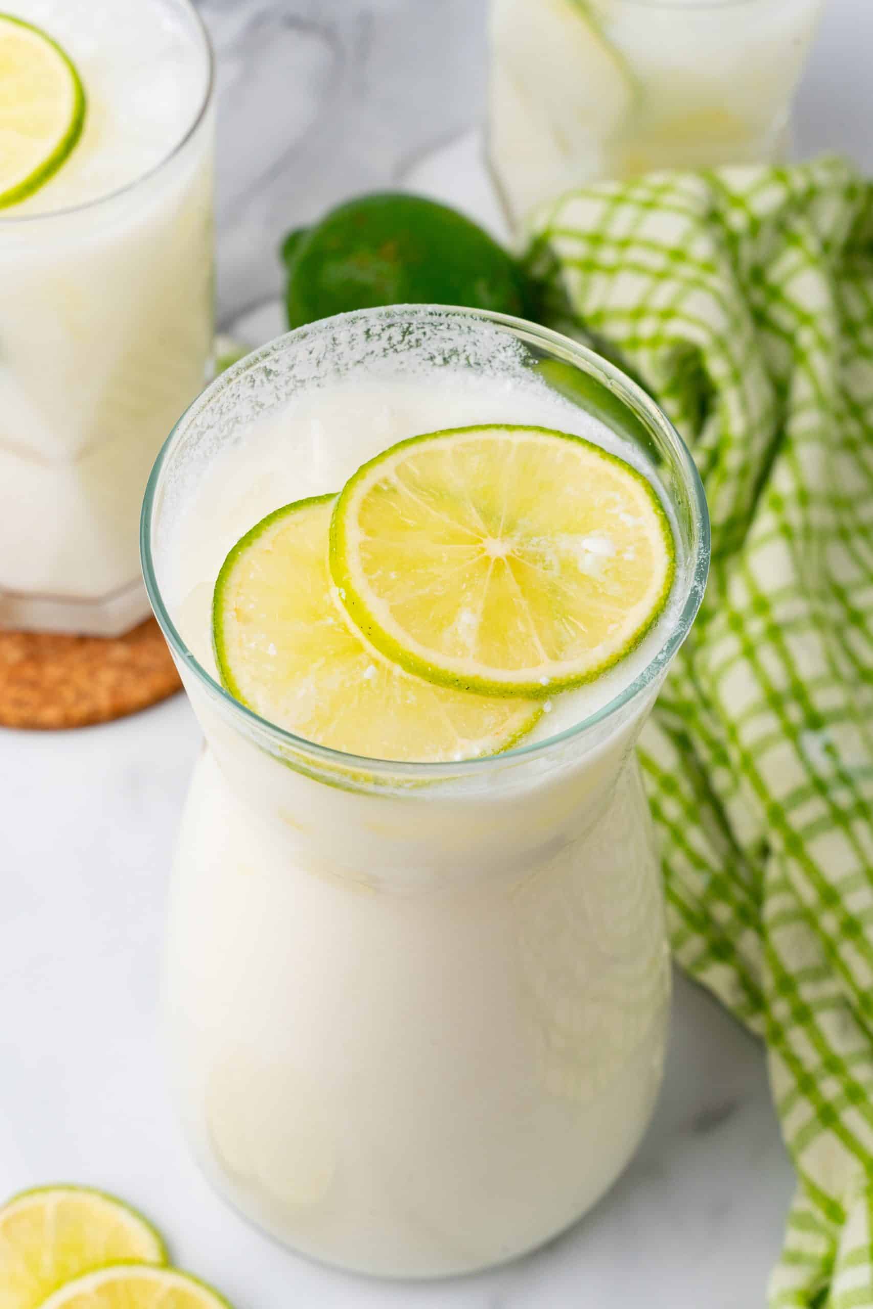 easy creamy limeade in a pitcher topped with fresh slices of lime