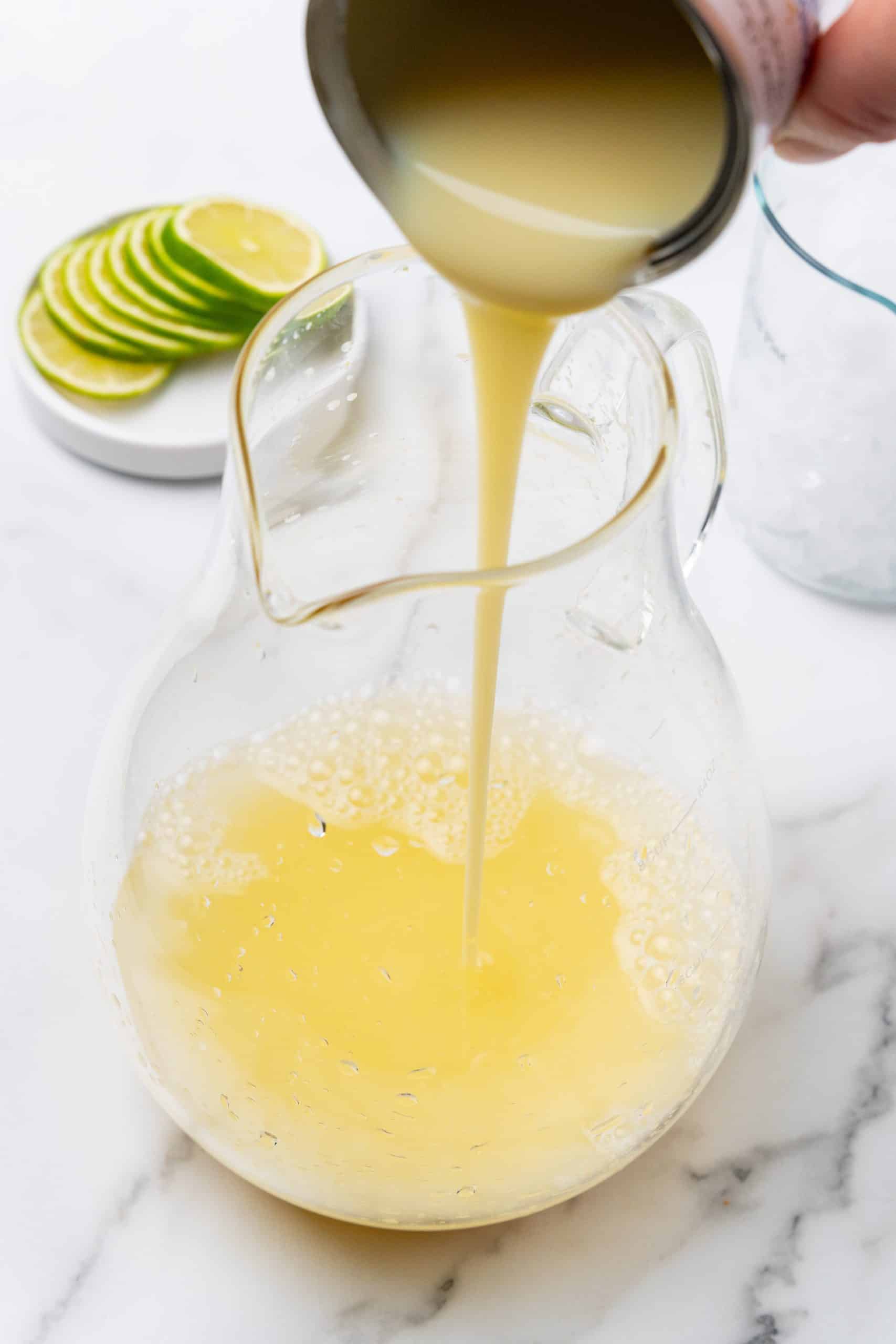 a can of sweetened condensed milk being poured into a large glass pitcher