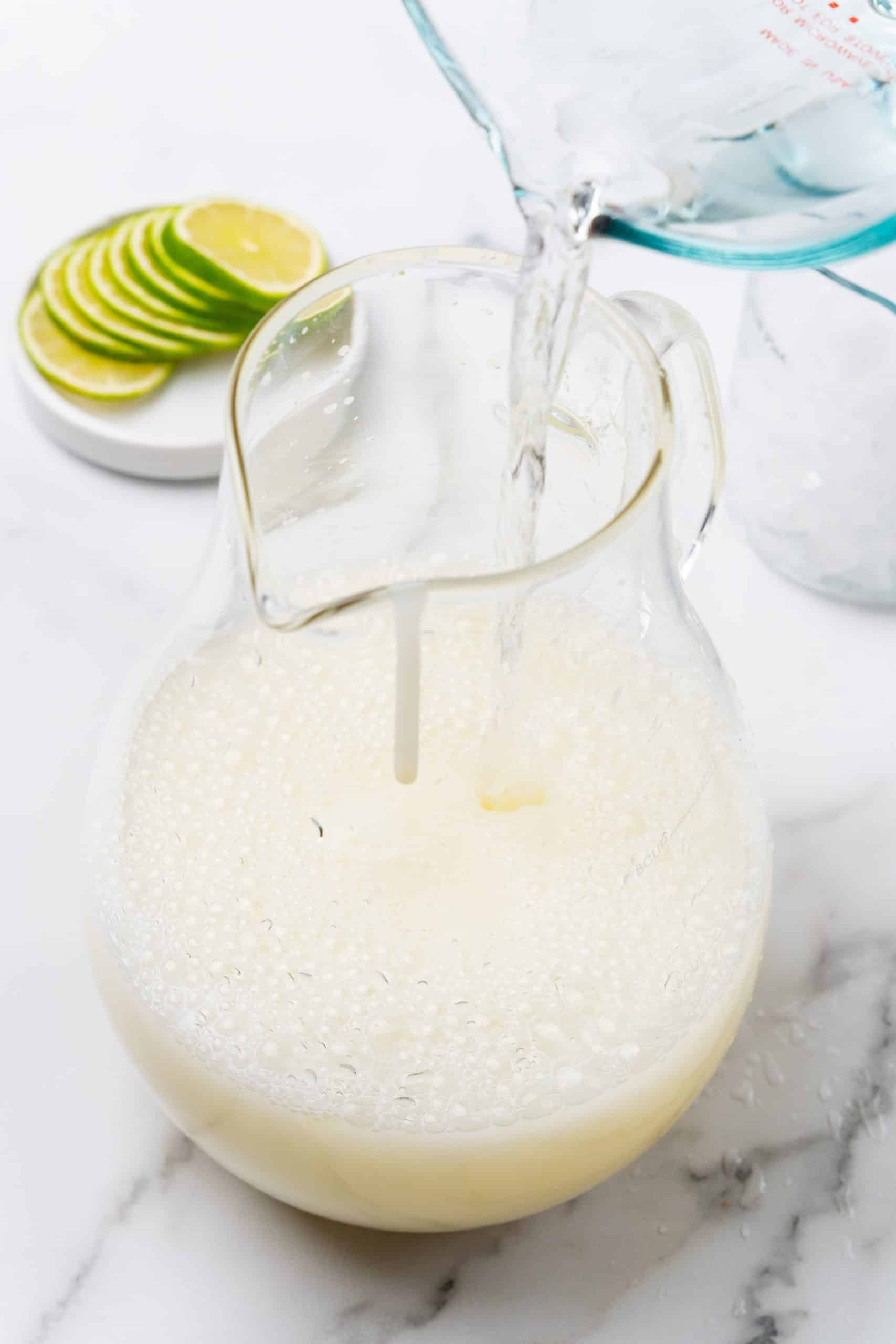 water being poured into a large glass pitcher
