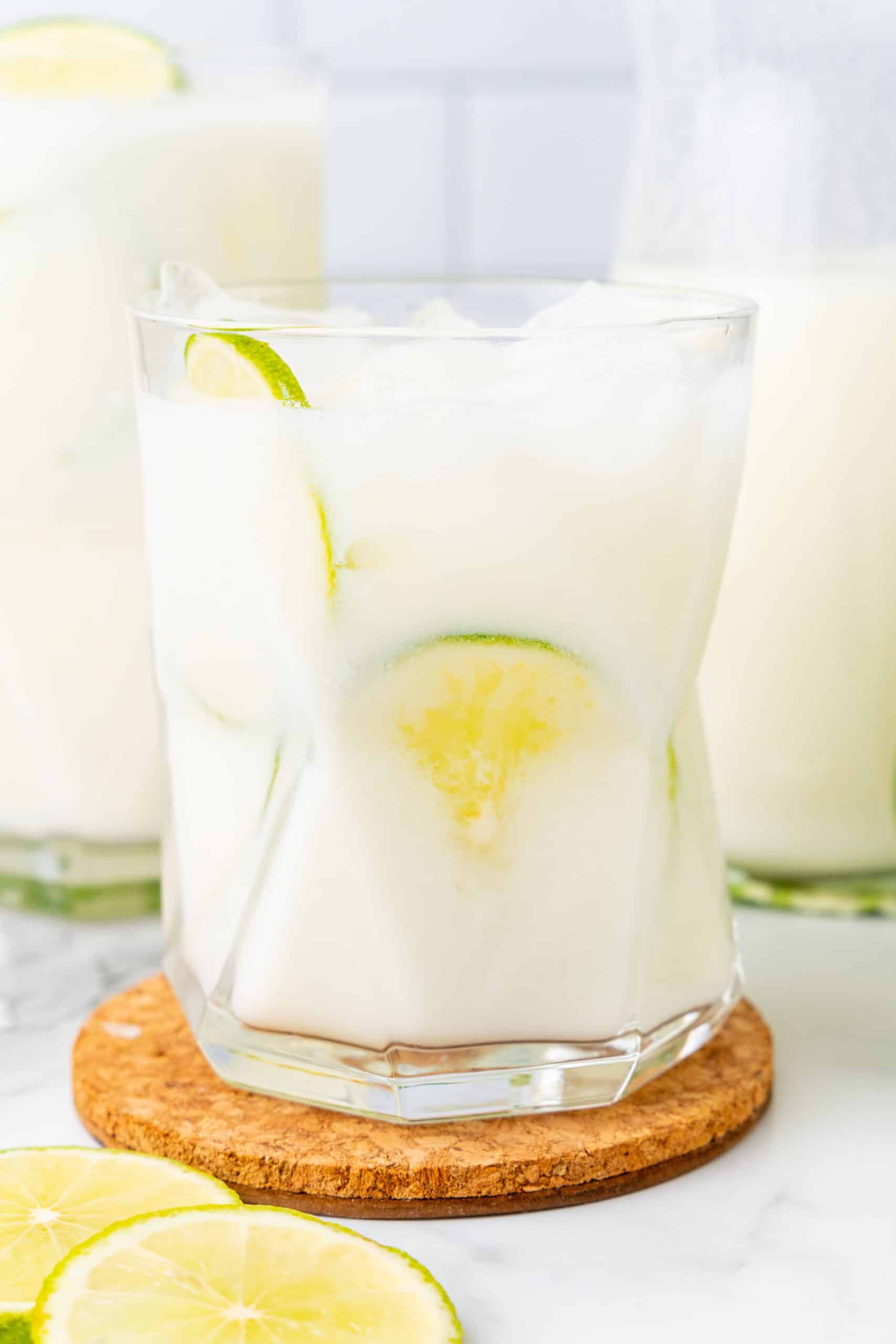 creamy Brazilian lemonade in a drinking glass with slices of lime and ice cubes