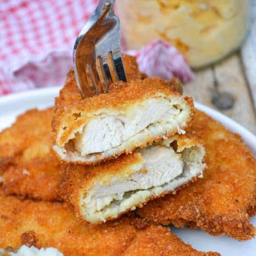 two halves of a piece of potato flake chicken on a silver fork