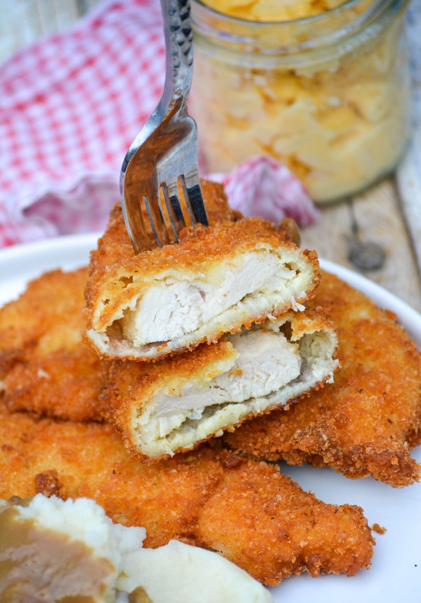 two halves of a piece of potato flake chicken on a silver fork