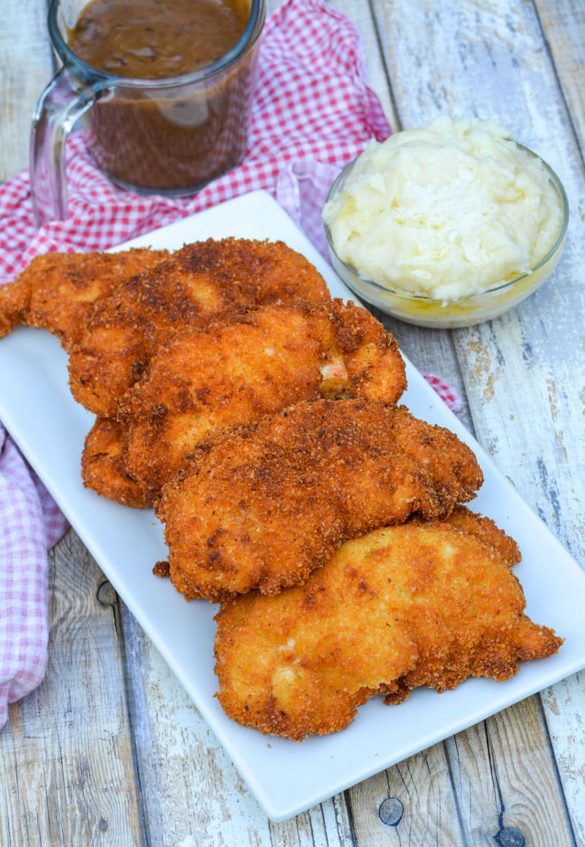 crispy potato flake chicken tenders stacked on a white serving platter