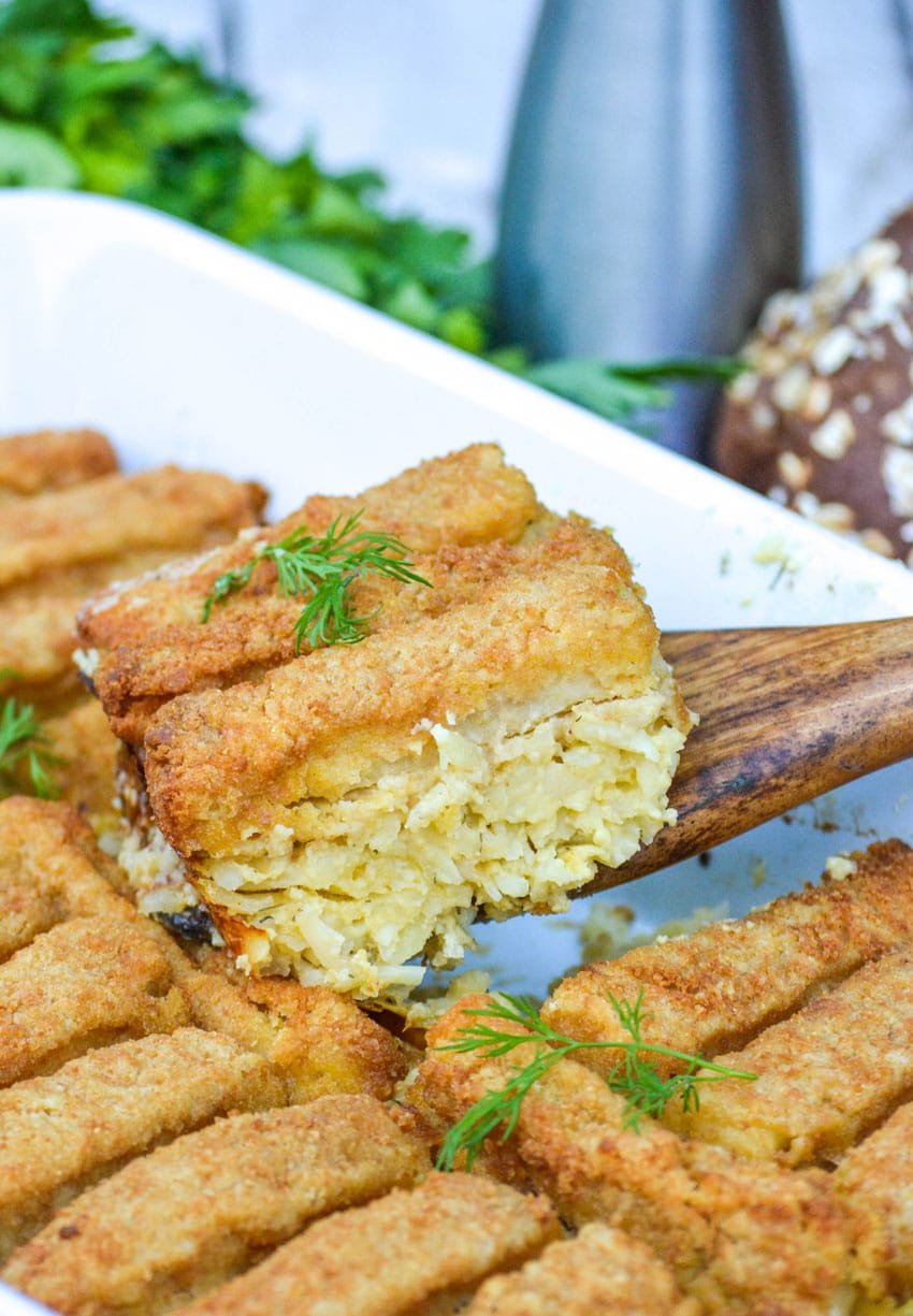 a wooden spatula holding up a slice of frozen fish stick casserole
