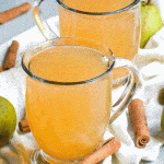 instant pot pear cider in two clear glasses surrounded by ripe pears and cinnamon sticks
