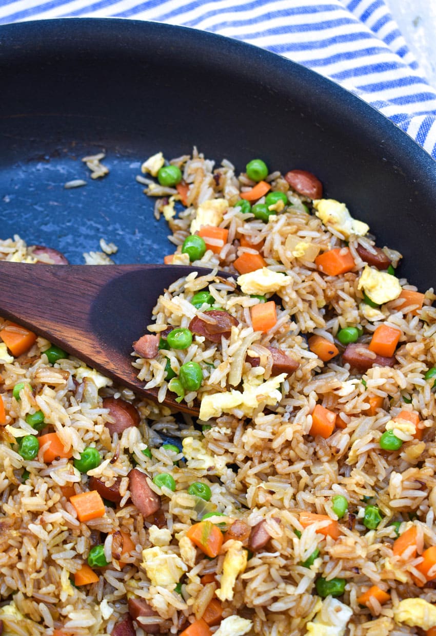 a wooden spoon stuck in a skillet of leftover hot dog fried rice
