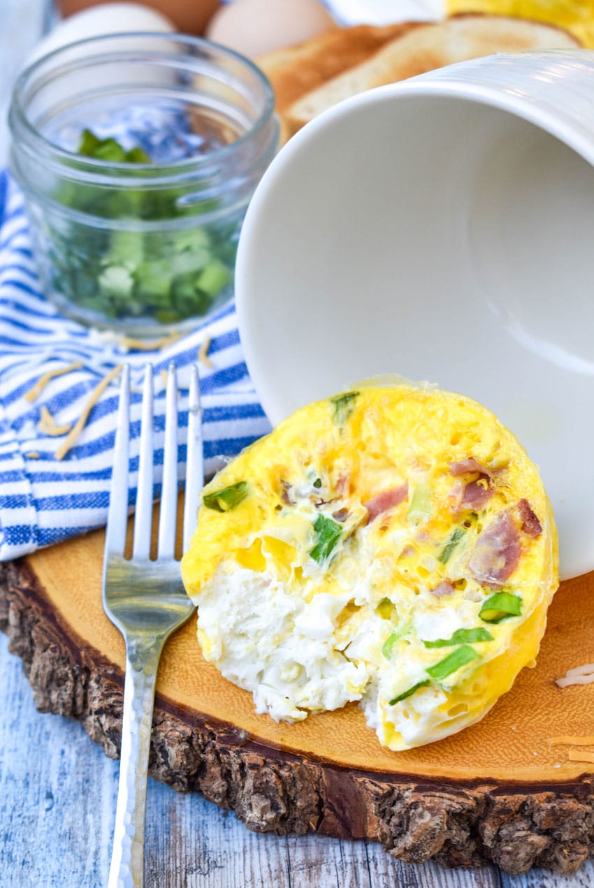 an omelet in a mug removed from the mug and resting on a wooden cutting board