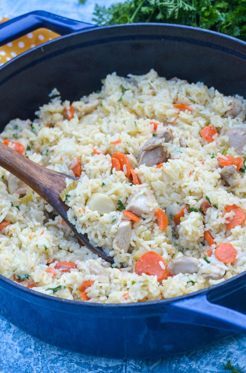 a wooden spoon in a skillet of one pot chicken and rice