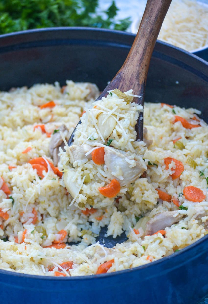 a wooden spoon holding up a scoop of one pot garlic chicken and rice