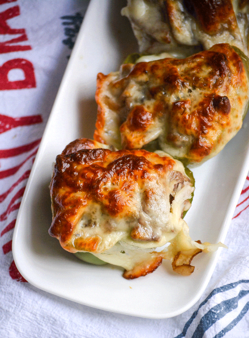 philly cheesesteak stuffed peppers in a row on a small white platter