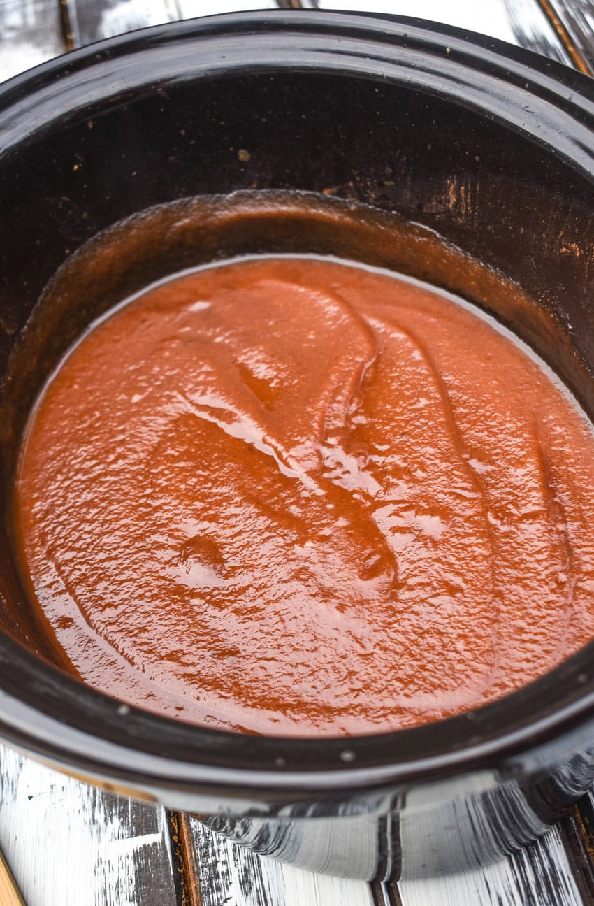 homemade apple butter in the black crock of a slow cooker