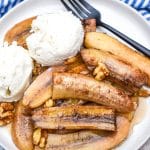 slow cooker bananas foster on a white plate topped with scoops of vanilla ice cream