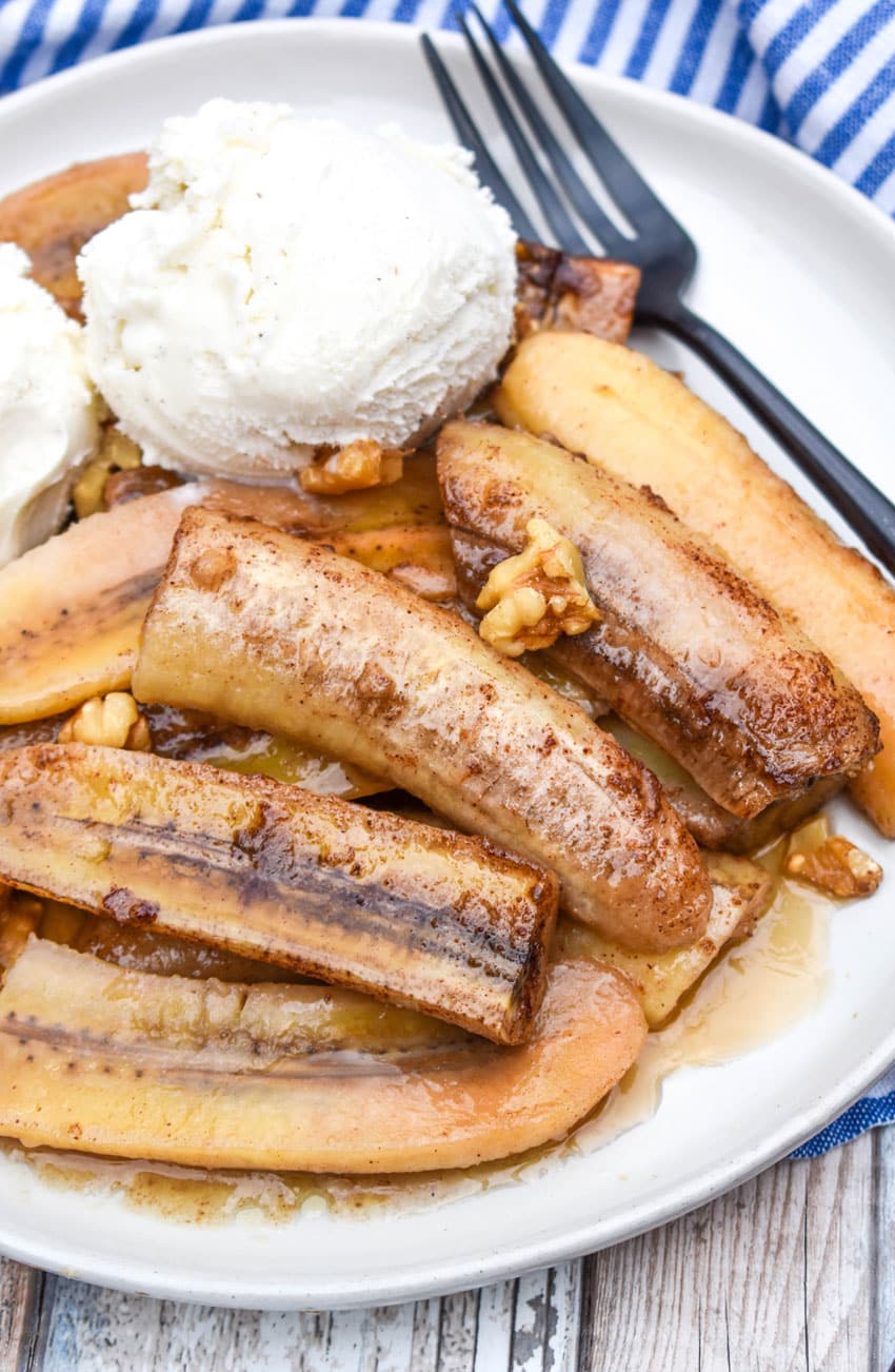 slow cooker bananas foster on a white plate topped with scoops of vanilla ice cream