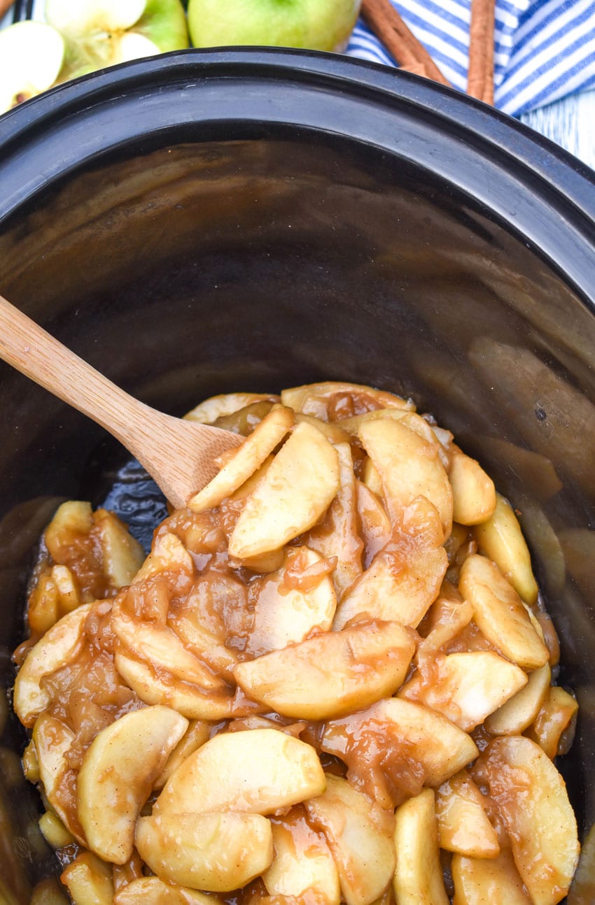 a wooden spoon stuck in a batch of crock pot fried apples