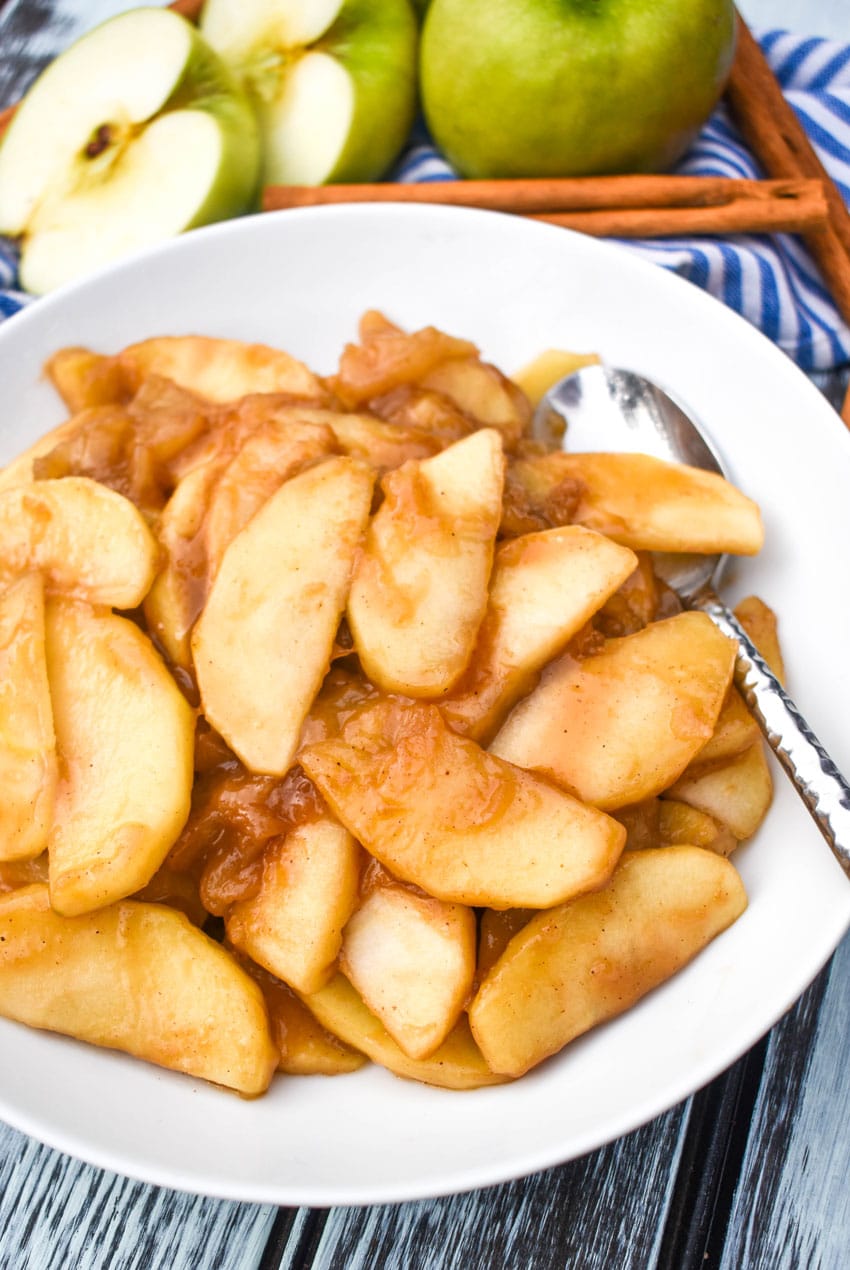 cracker barrel fried apples in a shallow white bowl with a silver spoon on the side