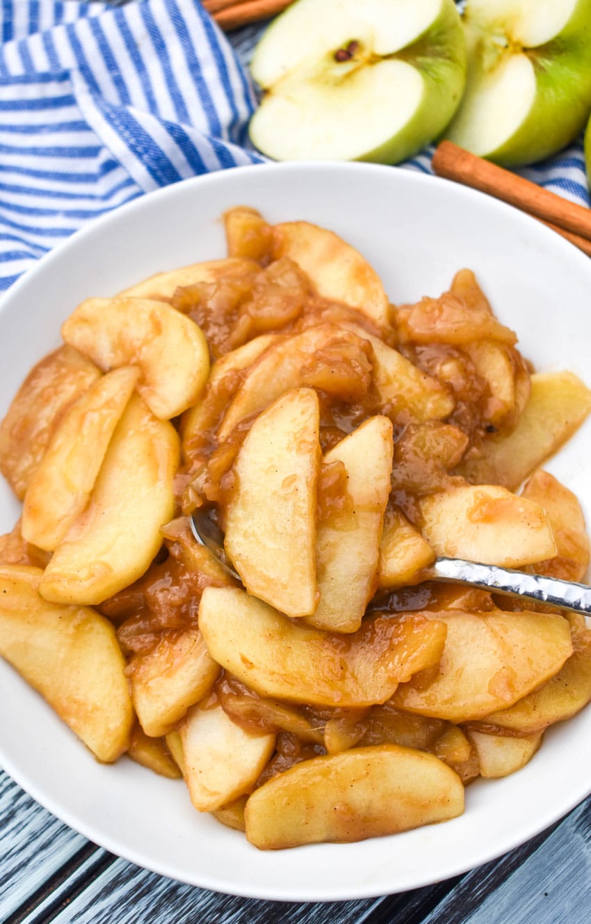 cracker barrel fried apples in a shallow white bowl with a silver spoon on the side