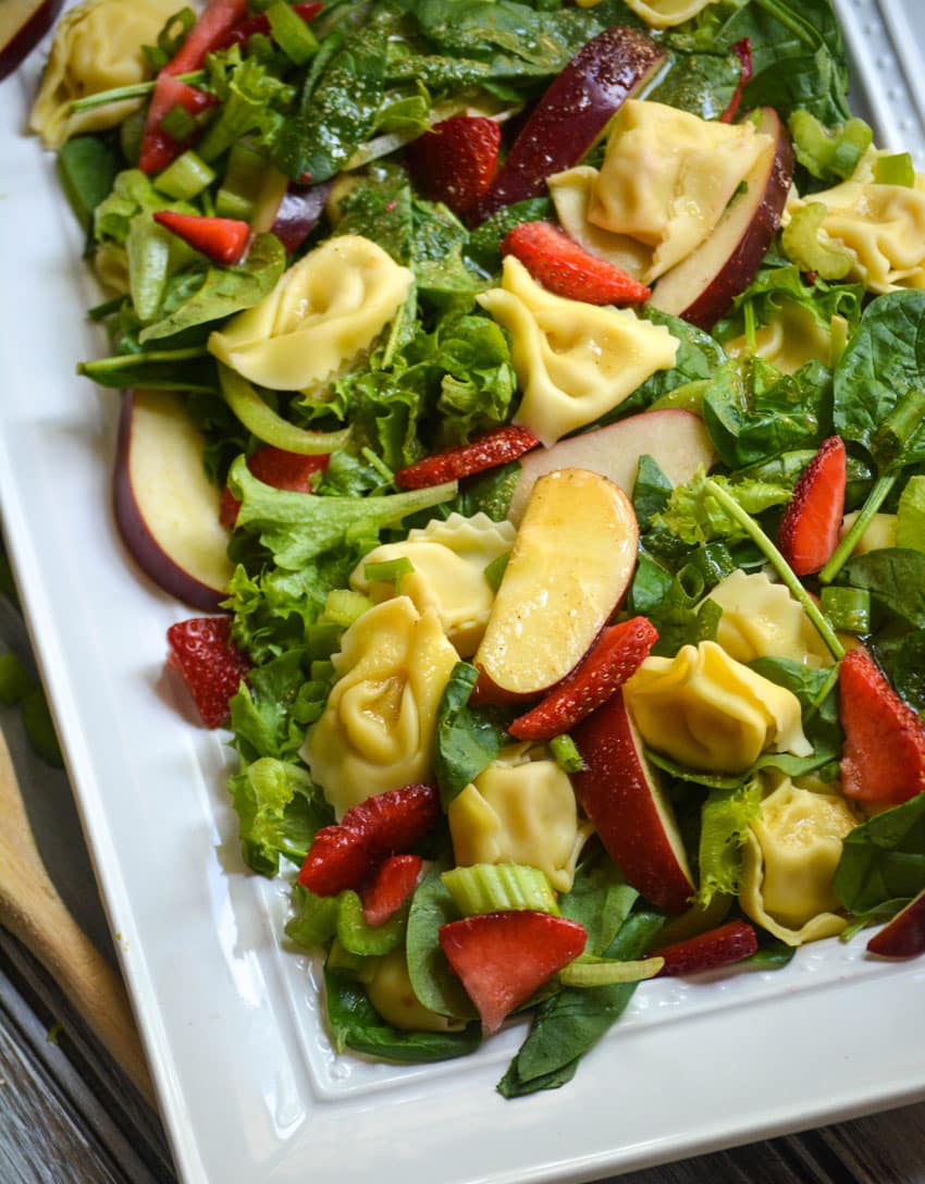 spinach tortellini salad on a white serving platter