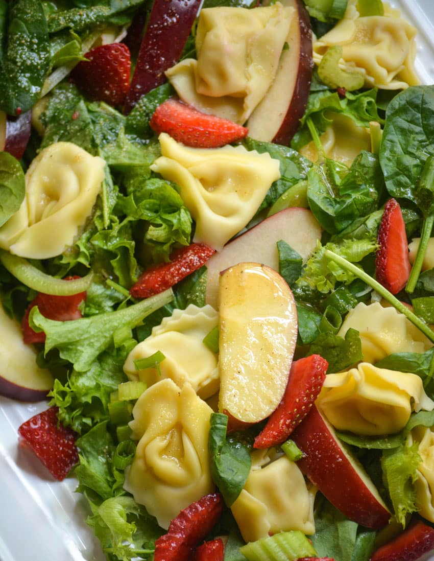 spinach tortellini salad on a white serving platter