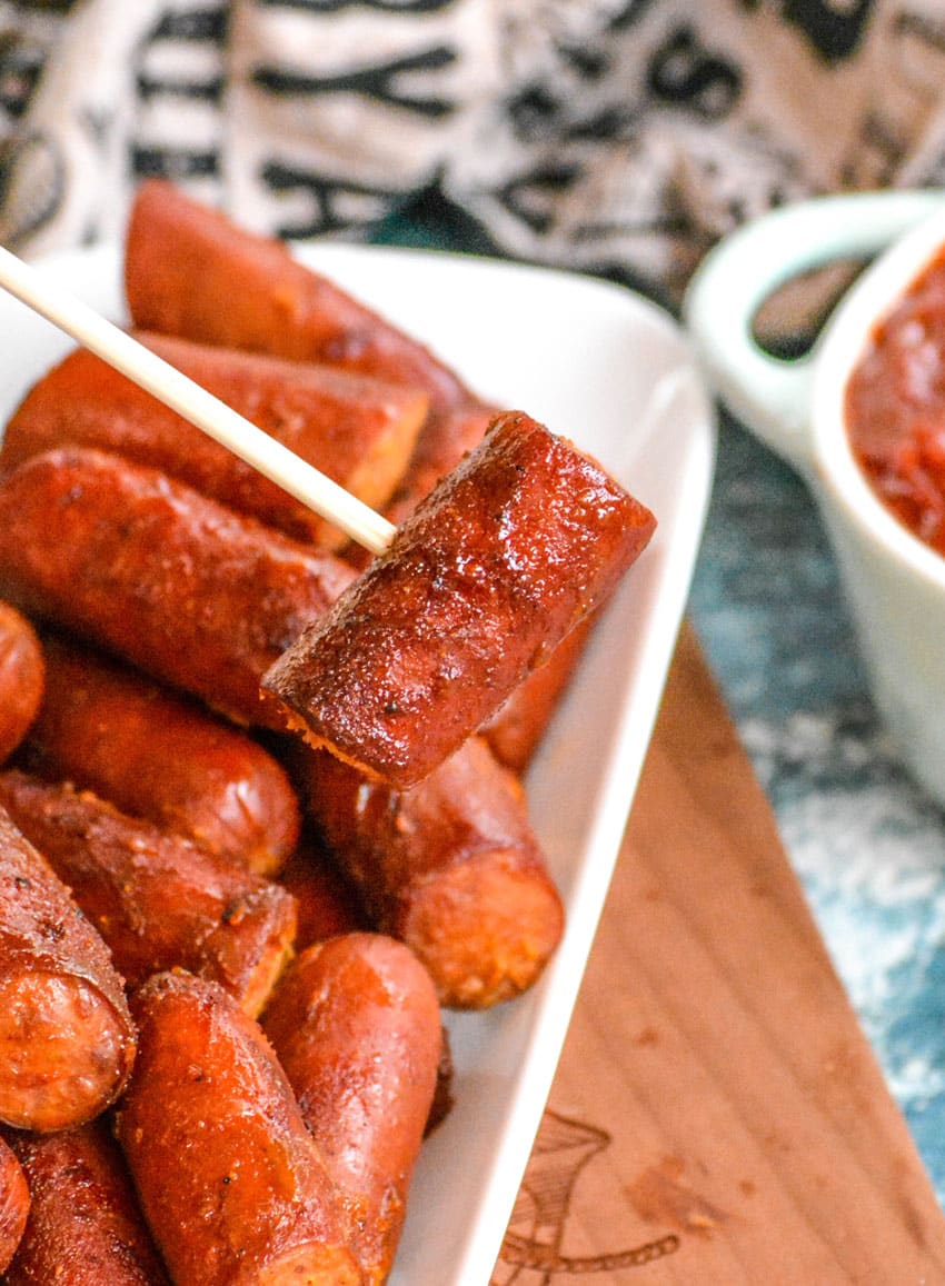 a wooden skewer holding up a smoked hot dog burnt end