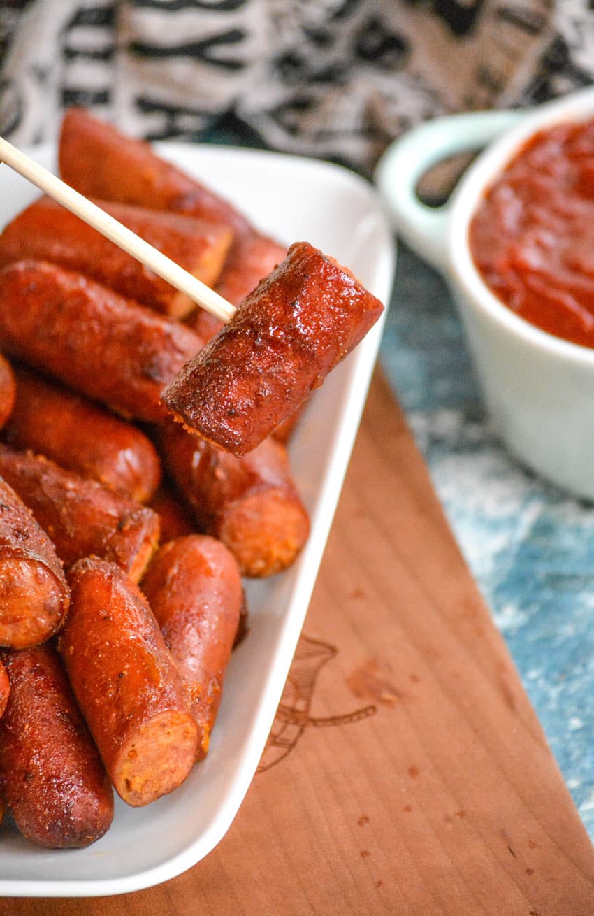 a wooden skewer holding up a smoked hot dog burnt end