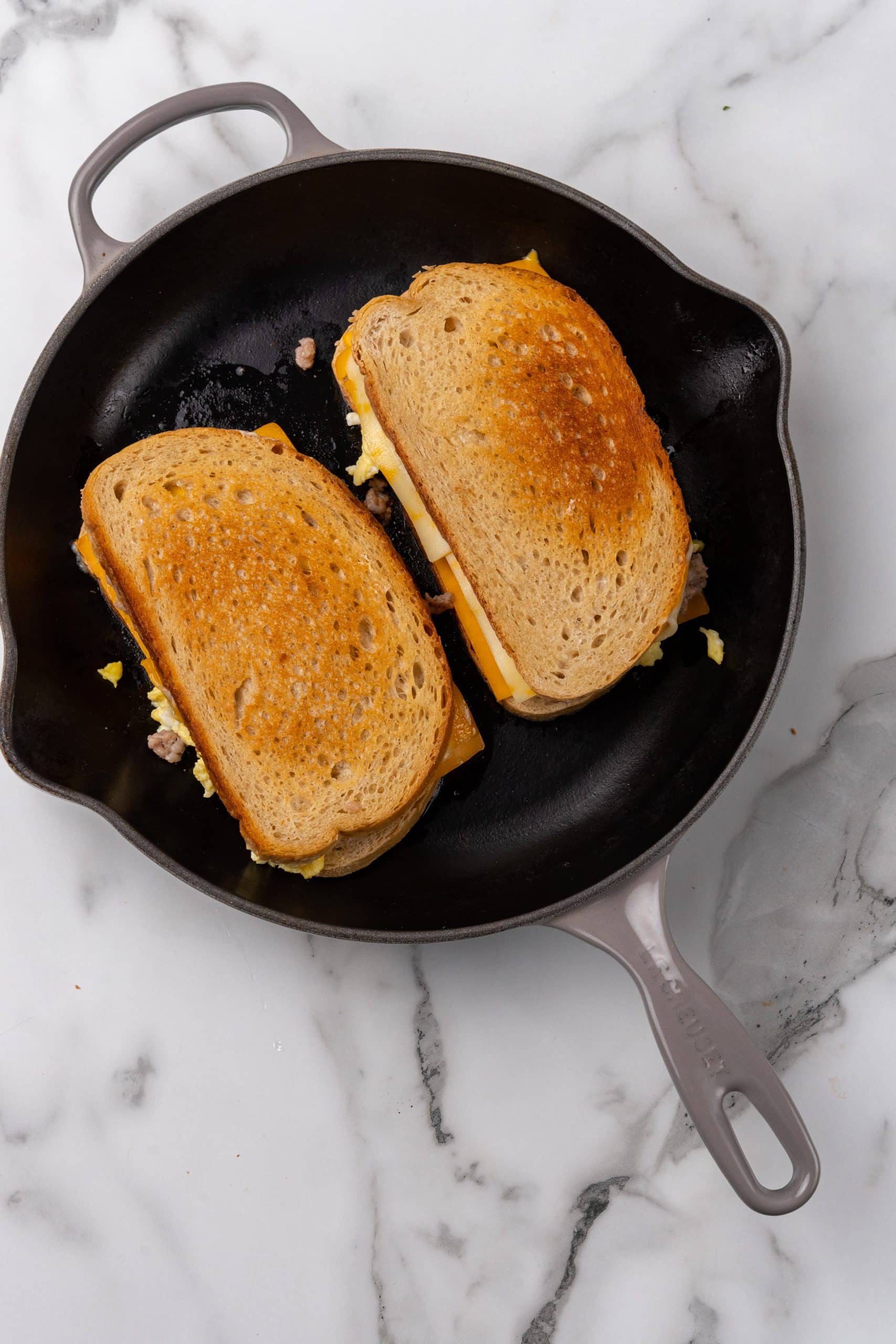 two grilled cheese and egg sandwiches in a black skillet