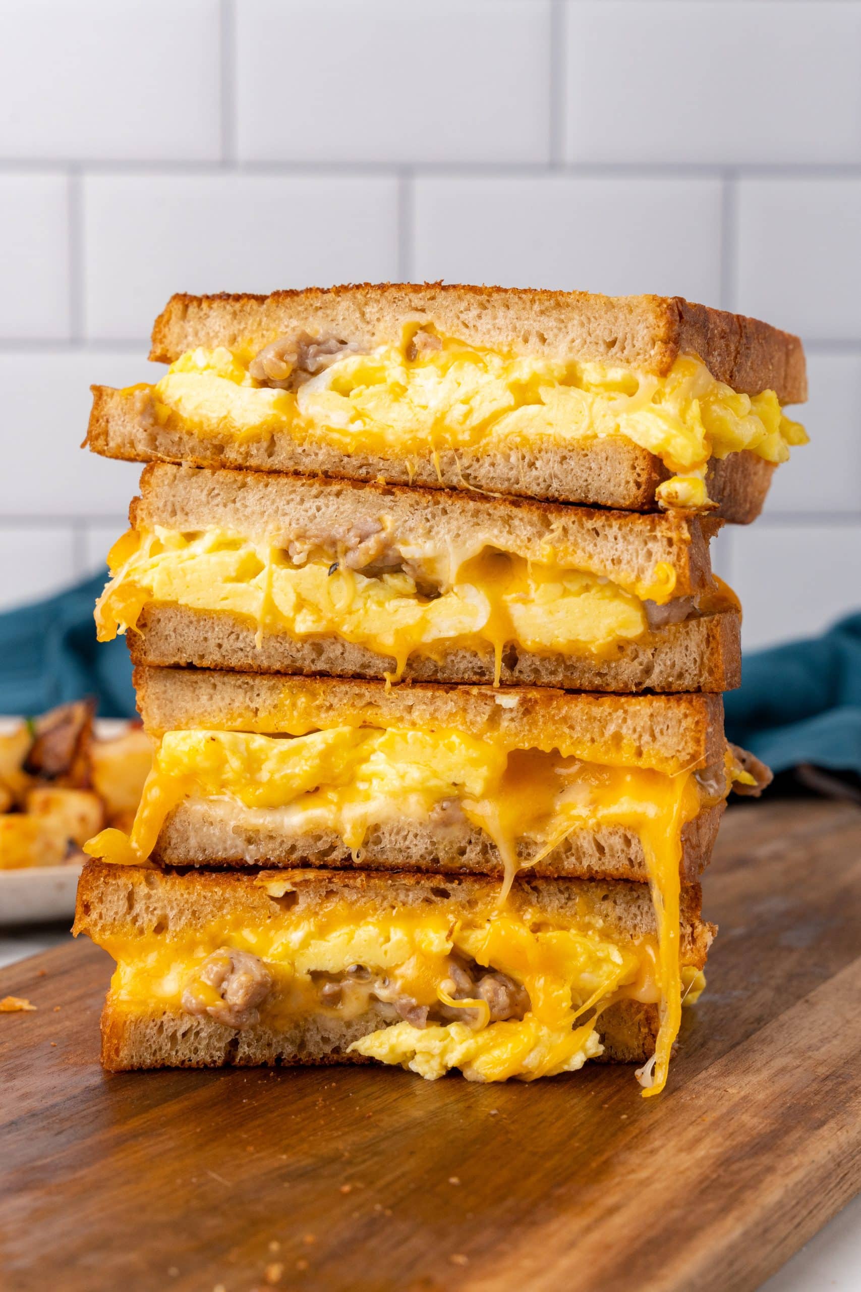 a stack of breakfast grilled cheese sandwiches on a wooden cutting board