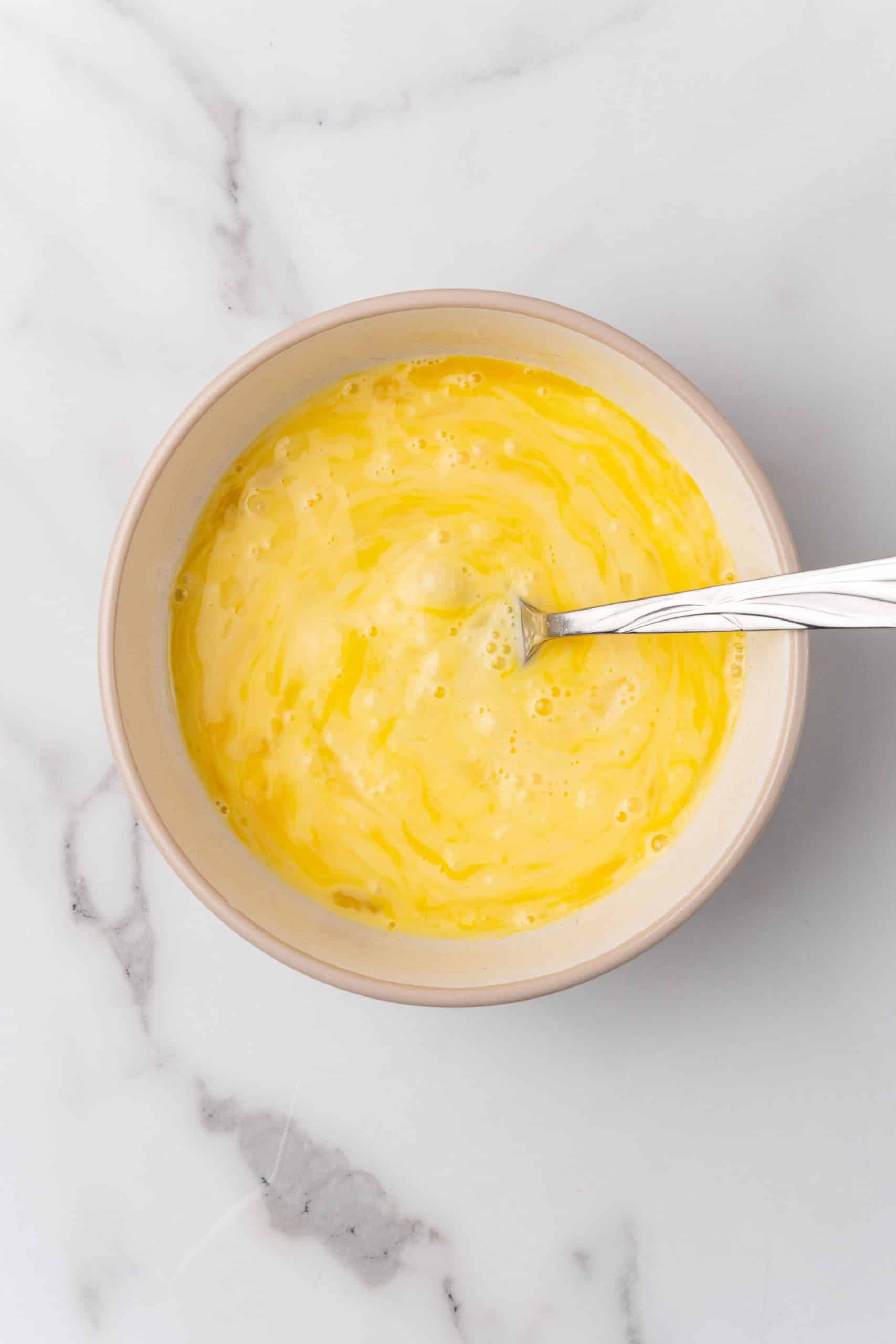 beaten eggs and cream in a small white bowl