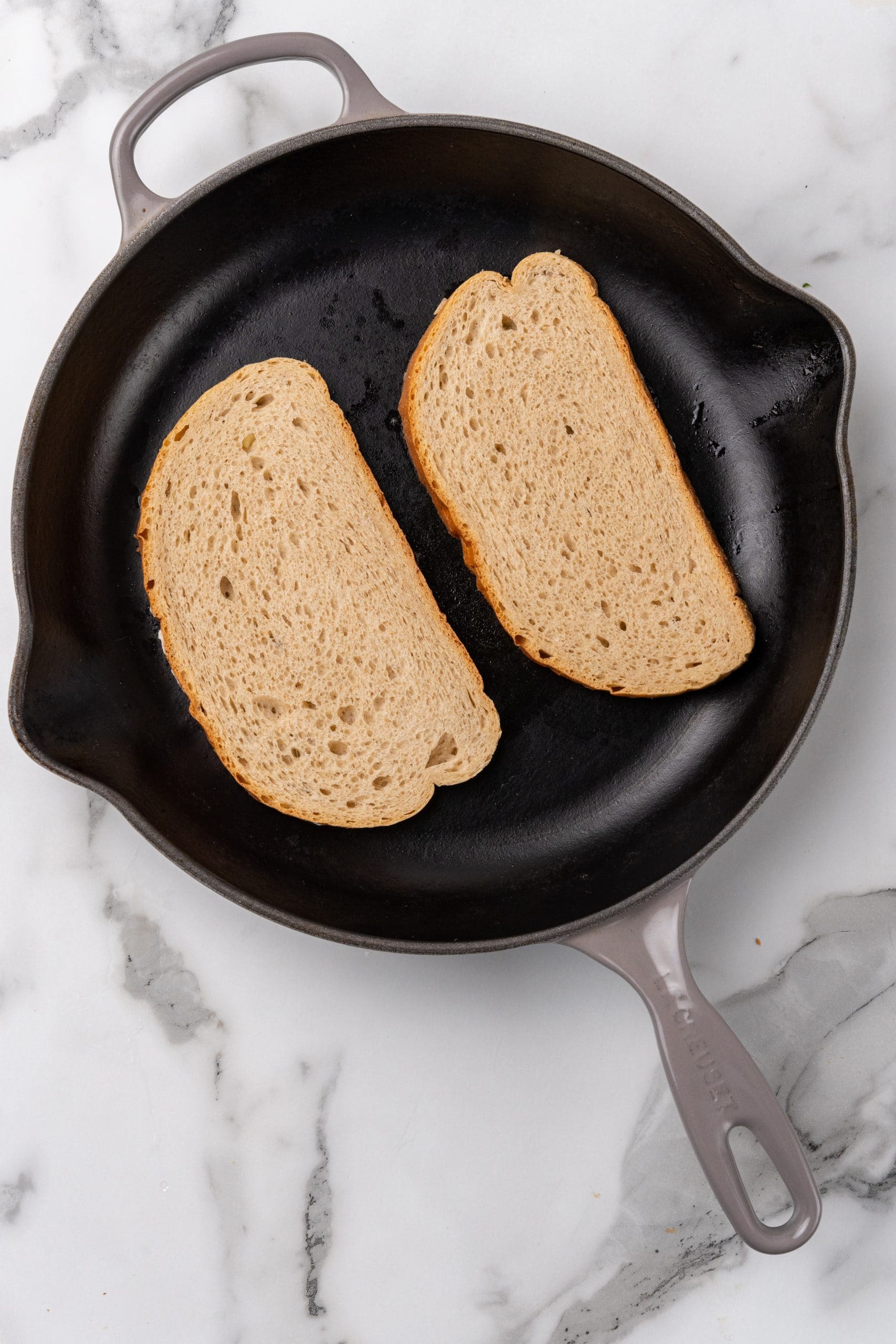 two buttered slices of bread in a small black skillet